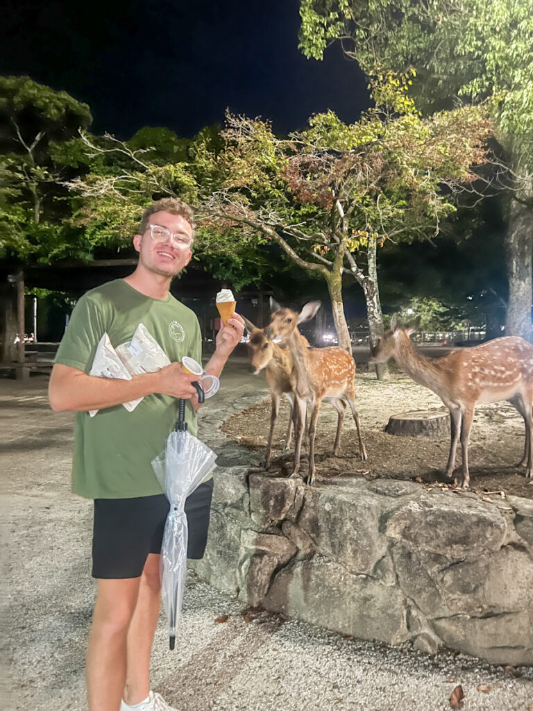 My partner holding an ice cream surrounded by deer.