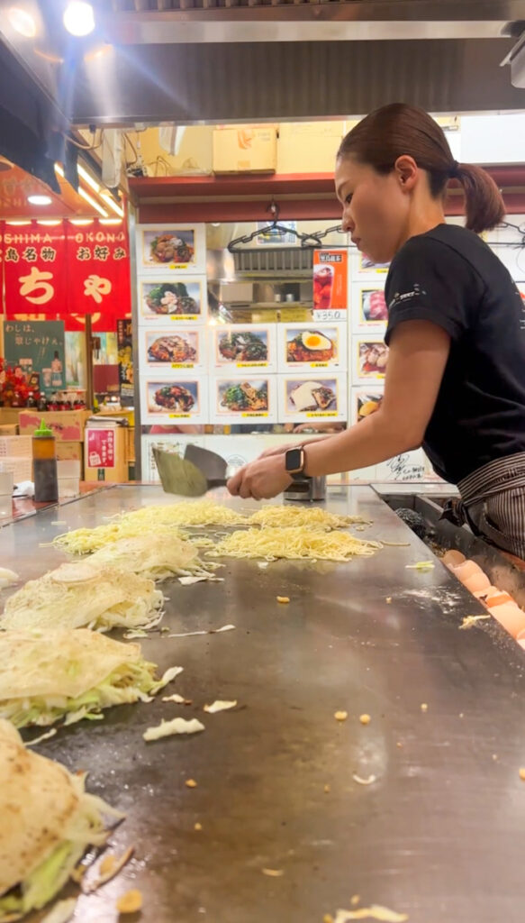 A woman preparing okonomiyaki in Hiroshima on our 10 day Japan itinerary.