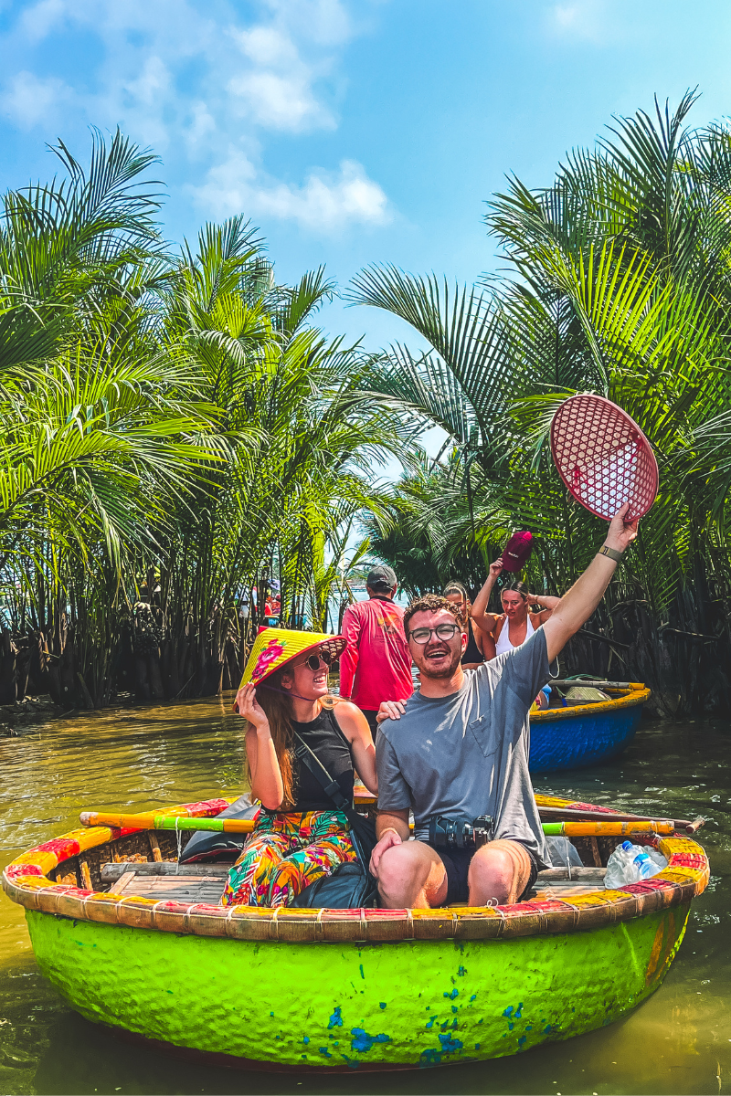 Jordyn and Jt in a barrel boat in Vietnam. JT is holding up a rice hat.
