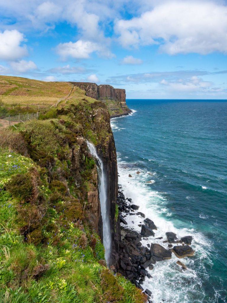 Huge cliff face with a waterfall going over it into the ocean. Kilt Rock and Mealt Falls