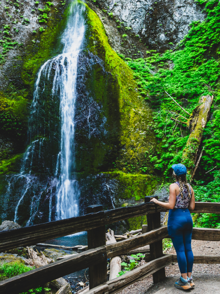 Woman admiring a lush waterfall near Seattle, a scenic hiking stop featured in this Seattle travel guide.