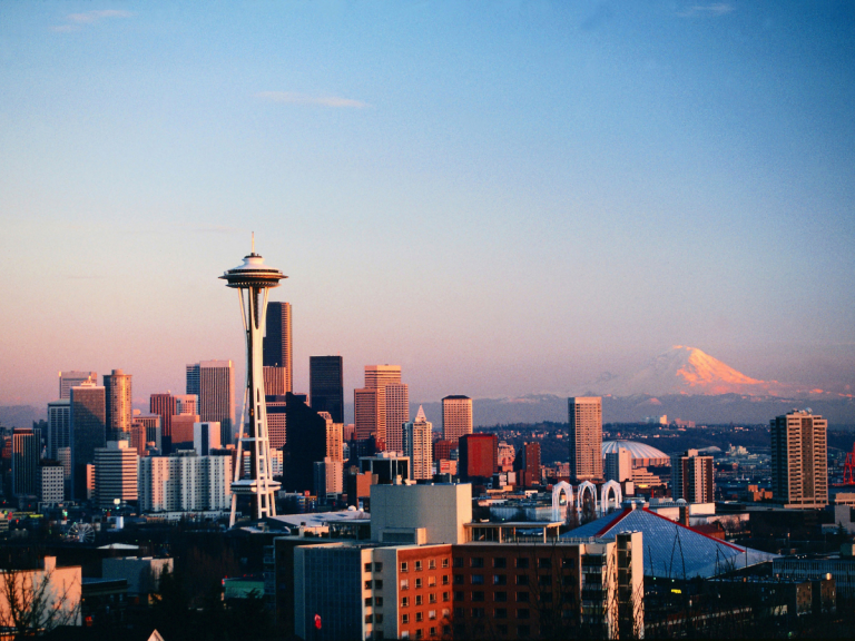 Sunset over Seattle with clear view of the Space Needle, city buildings, and snow-capped Mount Rainier