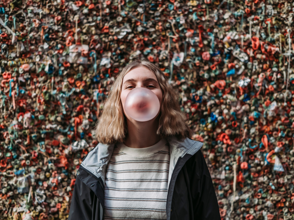 Traveler blowing a bubblegum bubble in front of Seattle’s famous Gum Wall, a quirky stop featured in this Seattle travel guide.