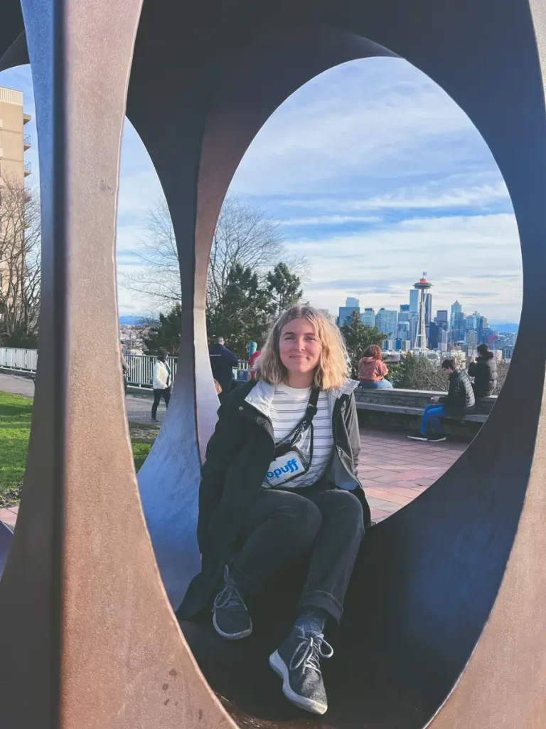 A person sitting inside a sculpture at Kerry Park with the Seattle skyline and the Space Needle framed perfectly in the background, one of the city's most iconic viewpoints.