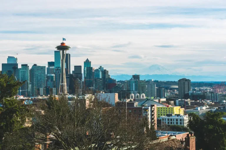 The Seattle skyline viewed from Kerry Park, featuring the Space Needle in the foreground and Mount Rainier rising in the distance beneath a cloudy sky in Seattle, Washington.