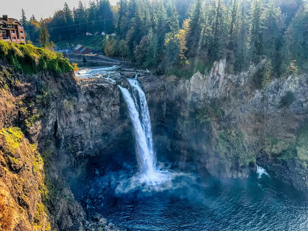 Snoqualmie Falls cascading 268 feet into the Snoqualmie River below, surrounded by rugged cliffs and evergreen forests in Washington.