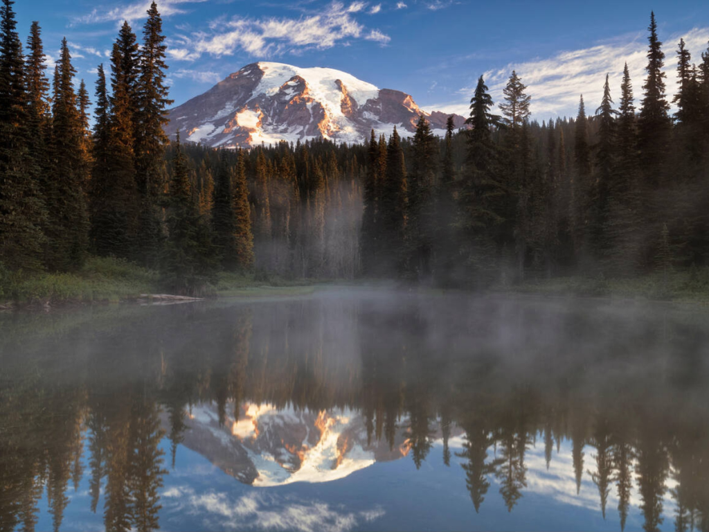 Mount Rainier reflected in a misty lake at sunrise, a peaceful moment captured during a Mount Rainier 2 day itinerary.