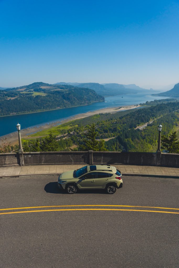 Car parked at Crown Point Vista House overlooking the Columbia River Gorge with sweeping river and mountain views