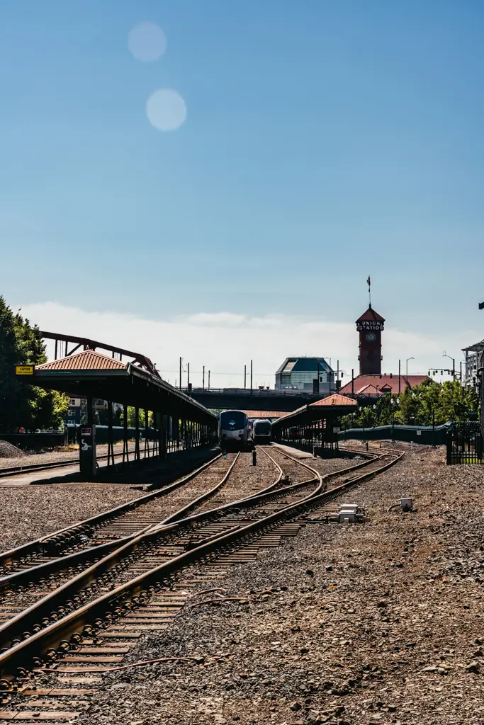 Railroad tracks leading toward Portland Union Station in Portland, Oregon, with trains at the platforms and the station’s historic clock tower rising in the background.