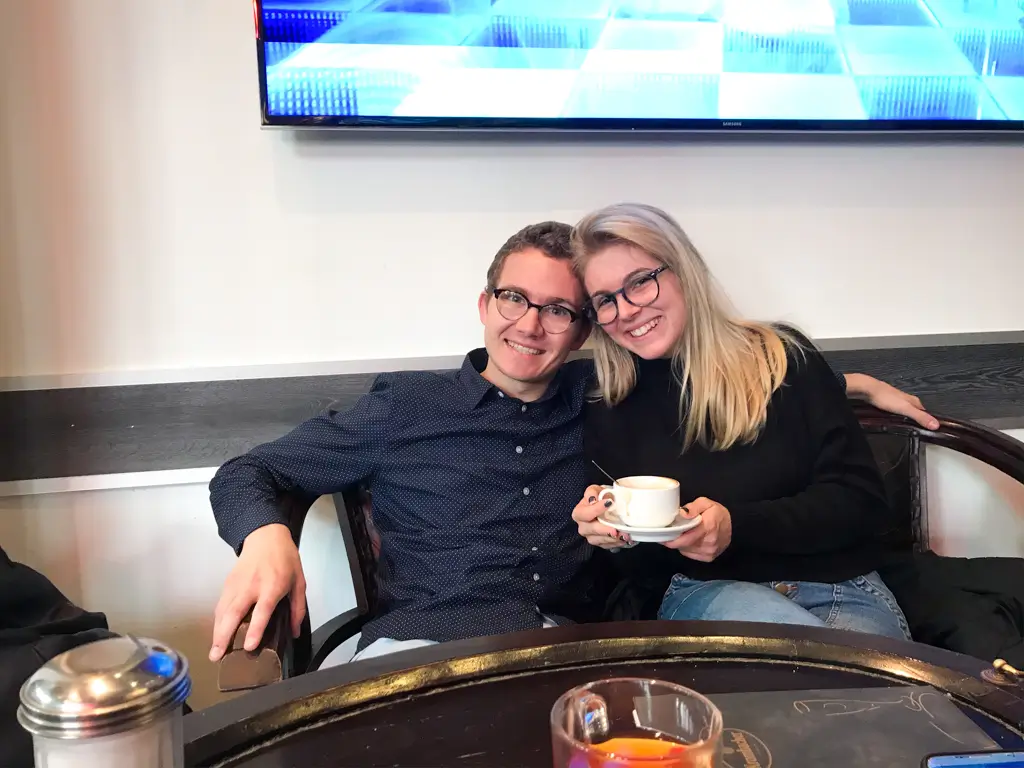 Couple smiling together over coffee at a cozy café during their travels through Europe.