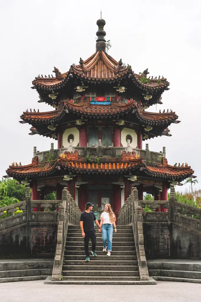 Couple walking down the stone steps of the Dragon and Tiger Pagodas at Lotus Pond in Kaohsiung, Taiwan, surrounded by traditional Chinese architecture.