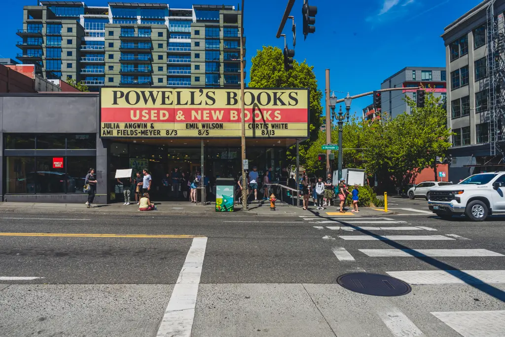 Exterior of Powell’s City of Books in downtown Portland, Oregon, featuring the iconic Powell’s Books marquee and visitors gathered outside on a sunny day.