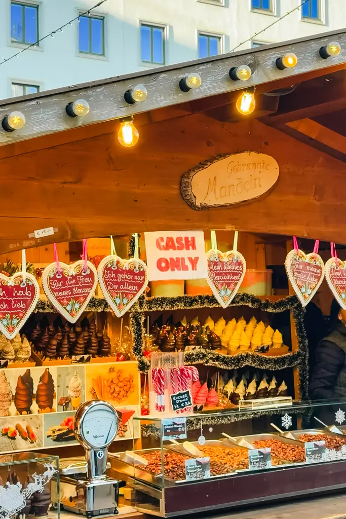 Cash only sign displayed at a festive European Christmas market stall selling roasted nuts, sweets, and holiday treats.