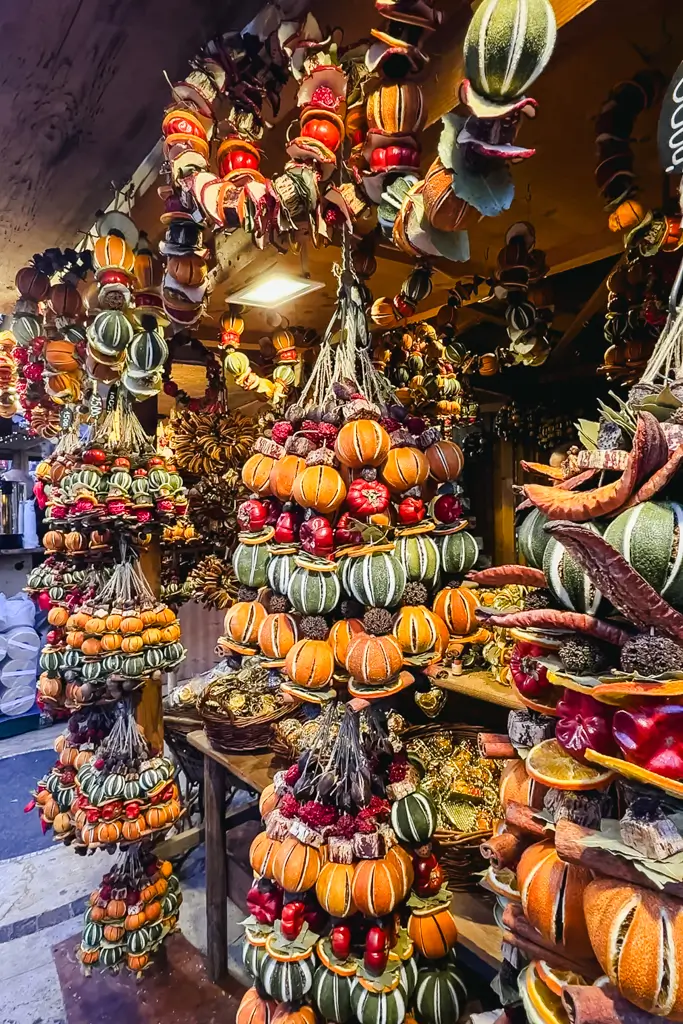 Handmade Christmas decorations crafted from dried oranges, apples, cinnamon, pinecones, and other natural materials at a European Christmas market.