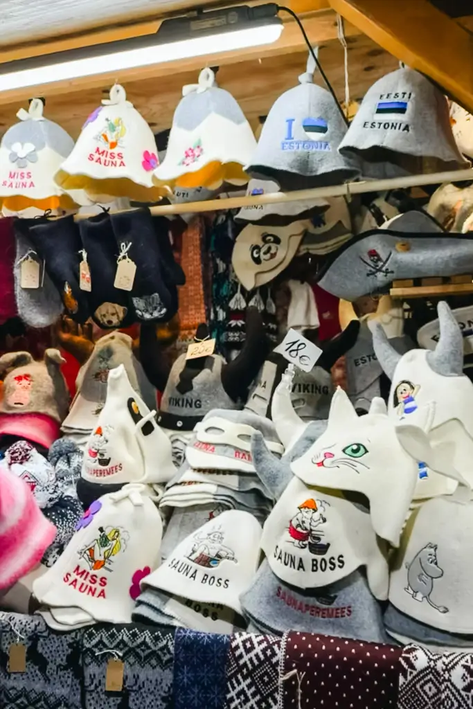 Traditional felt sauna hats with playful designs and Estonia souvenirs displayed at a Christmas market stall in Estonia.