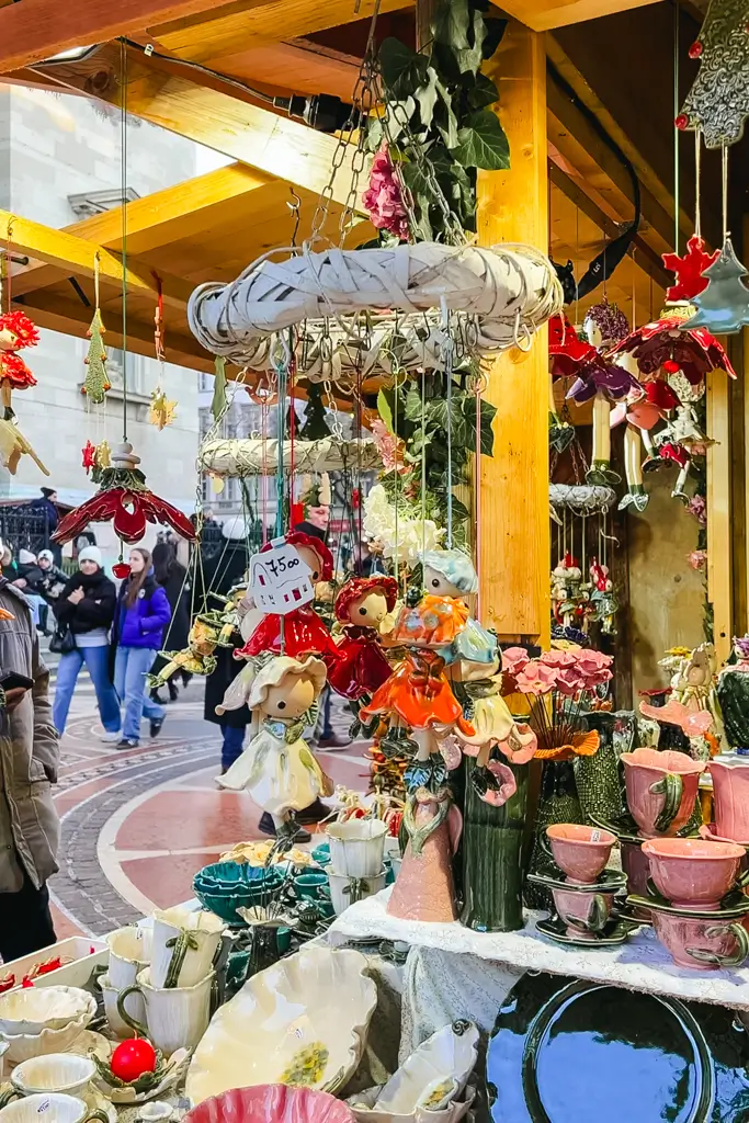 Colorful handmade ceramic ornaments, figurines, cups, and decorations displayed at a Christmas market stall in Budapest, Hungary.