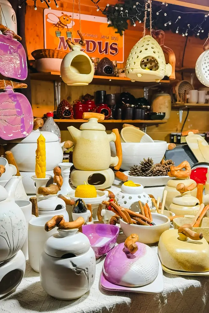 Handmade ceramic teapots, bowls, dishes, and hanging decorations with natural wood accents displayed at a European Christmas market.
