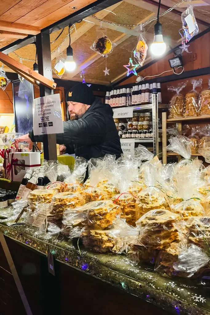 Vendor selling bags of traditional snacks, baked goods, syrups, and other local foods at the Wrocław Christmas Market in Poland.